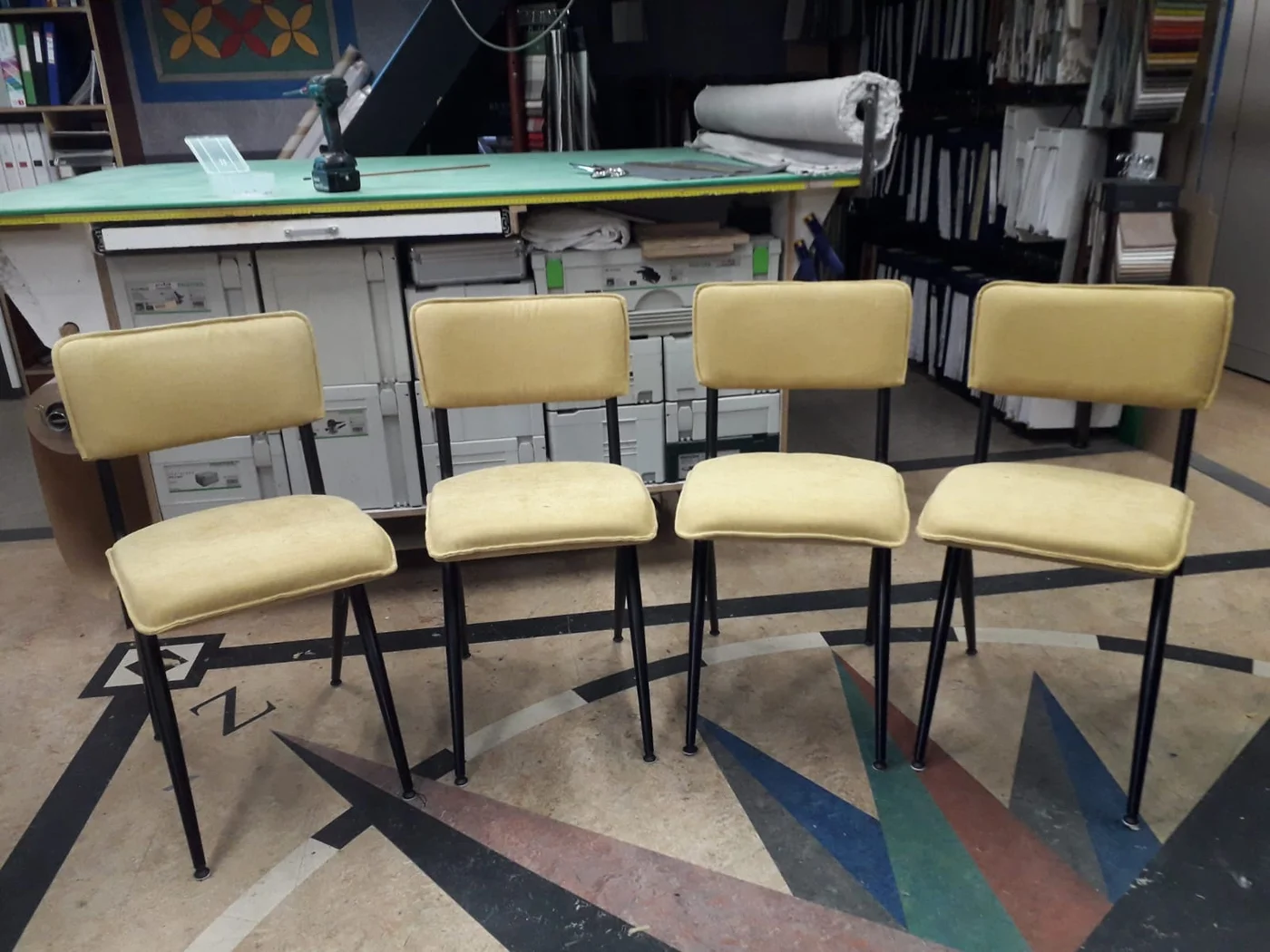 Vier stoelen met zachtgele bekleding en zwarte metalen poten in Jans werkplaats